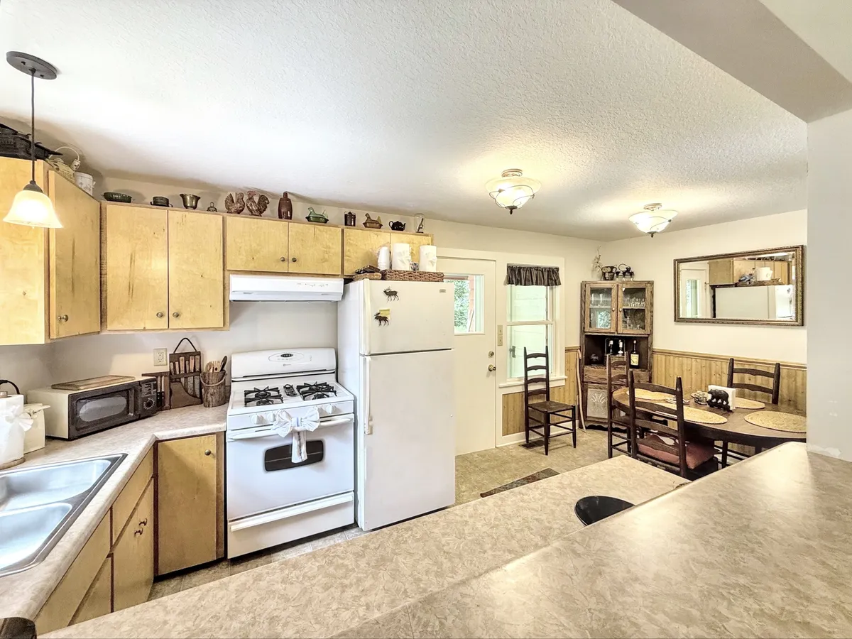 A cozy dining area adjacent to the kitchen, showcasing modern appliances, cabinetry, and a spacious dining table set for a meal. The space feels intimate and conducive to gatherings, with seating that encourages conversation and shared experiences.