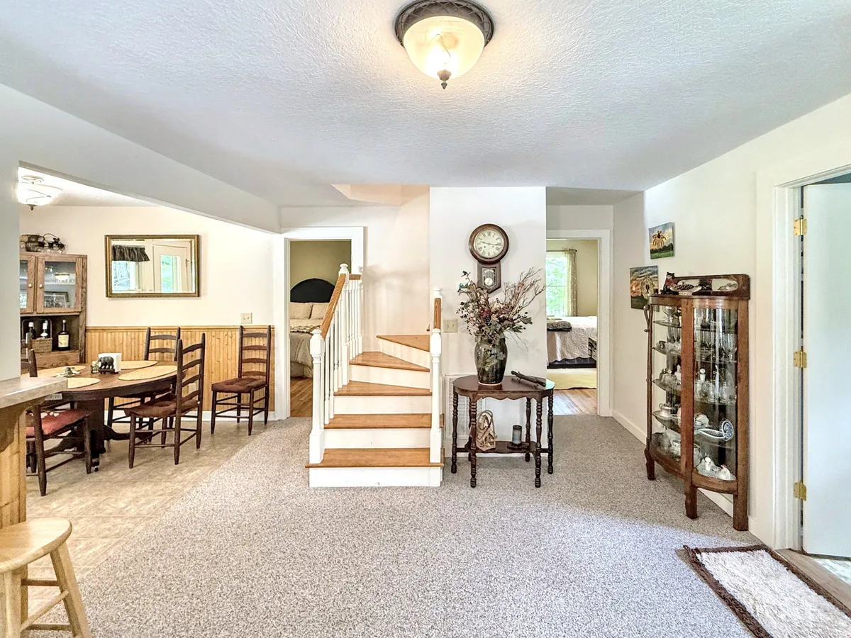 A welcoming dining area with a prominent dining table, surrounded by light and decorative touches. The staircase and display cabinet add warmth and a sense of family history, suggesting stories shared over meals.
