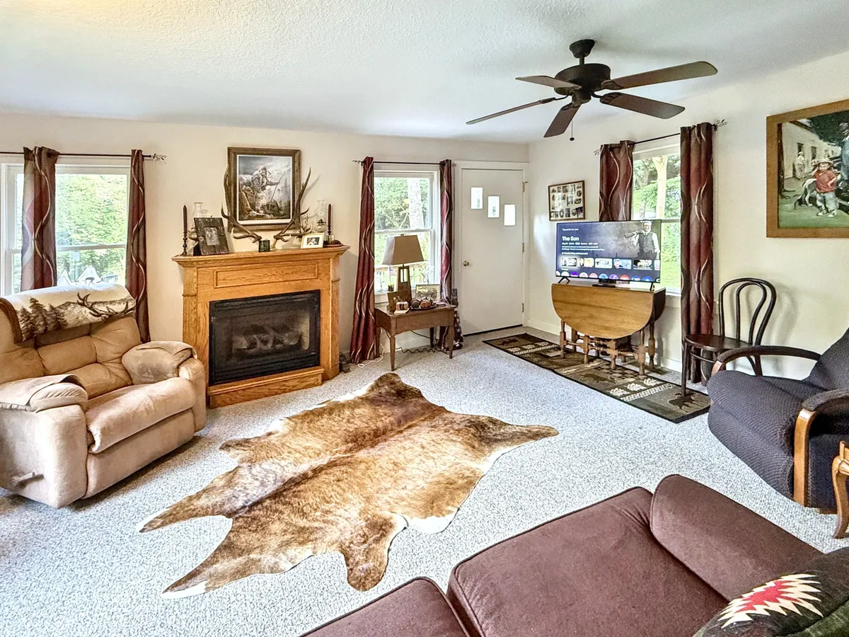 A cozy living room scene featuring a fireplace, a cowhide rug, a comfortable sofa, and a television. The inviting setting is ideal for gathering, socializing, and relaxing after a day of exploring the nearby downtown and mountains.